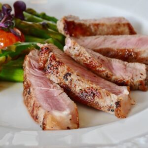 Close-up of grilled steak slices with asparagus and cherry tomatoes, perfect for a healthy meal.