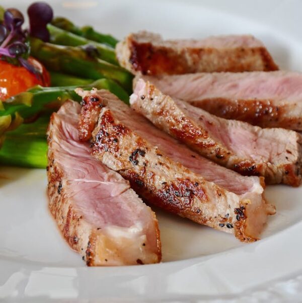 Close-up of grilled steak slices with asparagus and cherry tomatoes, perfect for a healthy meal.