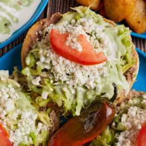 Delicious Mexican sopes topped with fresh lettuce, cheese, crema, and avocado salsa served in Monterrey.