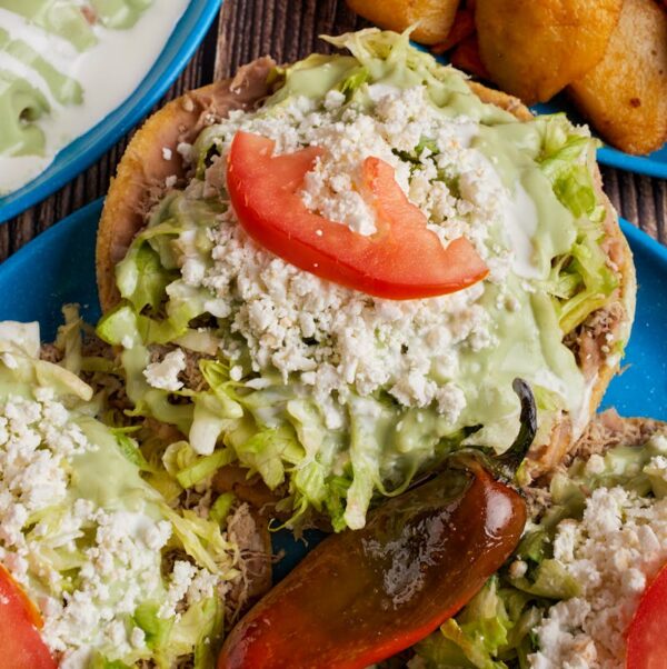 Delicious Mexican sopes topped with fresh lettuce, cheese, crema, and avocado salsa served in Monterrey.