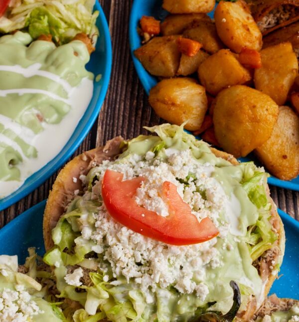Delicious Mexican sopes topped with fresh lettuce, cheese, crema, and avocado salsa served in Monterrey.