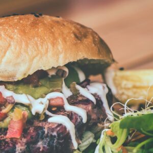 Delicious cheeseburger with fresh toppings and side of fries on a wooden board.