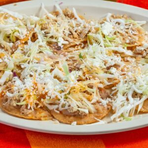 Delicious Mexican chilaquiles topped with sauce and cheese, served with fresh limes.