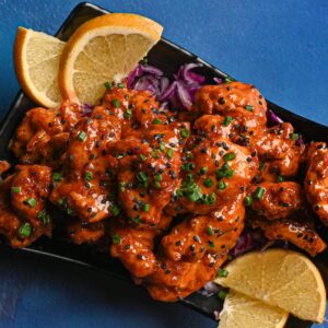 Tasty chicken dish garnished with lemon slices and fresh herbs on a vibrant blue backdrop.