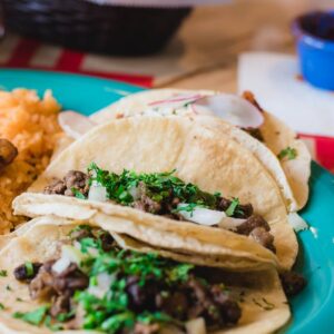 Mouth-watering Mexican tacos served with rice and beans, garnished with cilantro and lime.