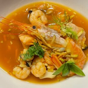A vibrant seafood soup featuring fresh shrimps and fish in a rich broth.
