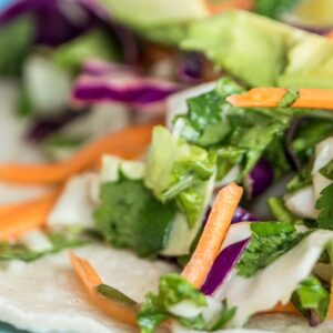 Close-up of a vibrant taco with fresh vegetables on a blue plate.