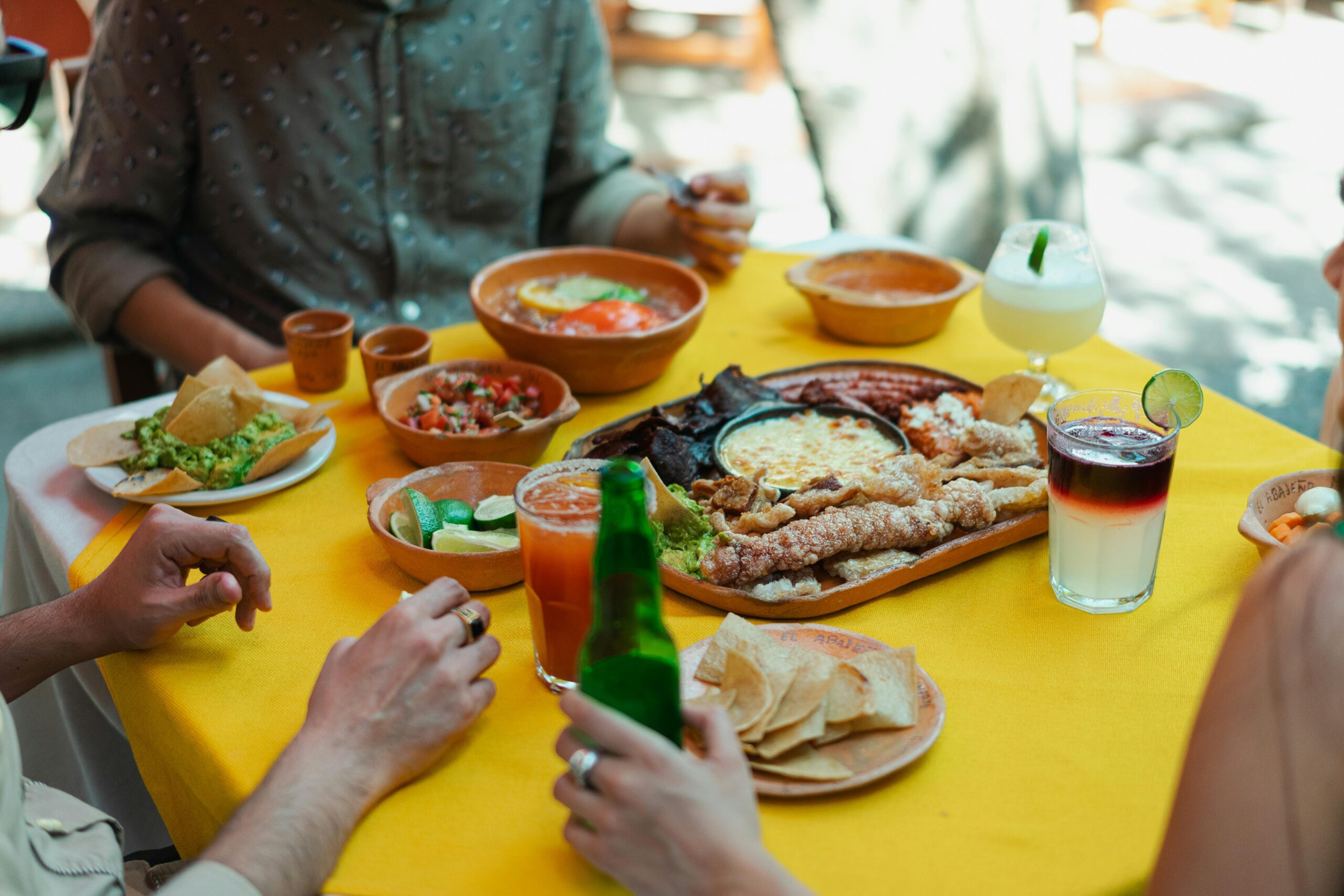Vibrant scene of Mexican food, drinks, and people enjoying meals outdoors.